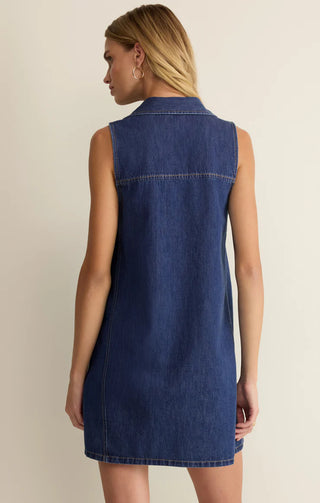 Woman wearing a blue denim dress against a beige background