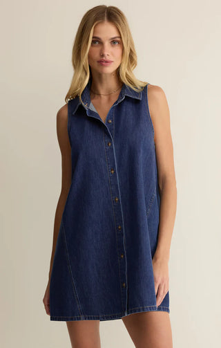 Woman wearing a denim dress against a beige background