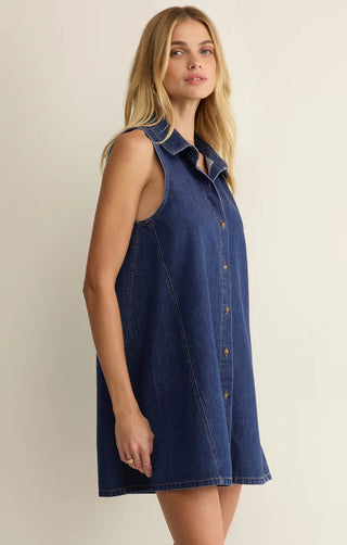 Woman wearing a blue denim dress against a beige background