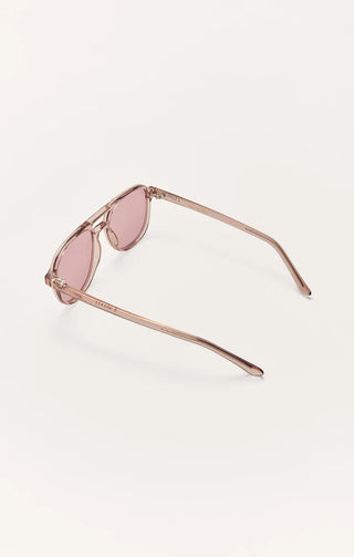 Sunglasses with pink lenses and rose gold frame on a light beige background