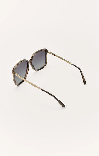 Sunglasses with tortoiseshell frame and dark lenses on a light gray background