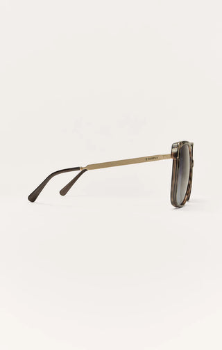 Sunglasses with a gold frame and dark lenses on a white background