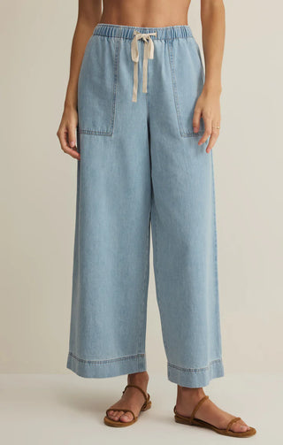 Light blue wide-leg pants worn by a person on a beige background