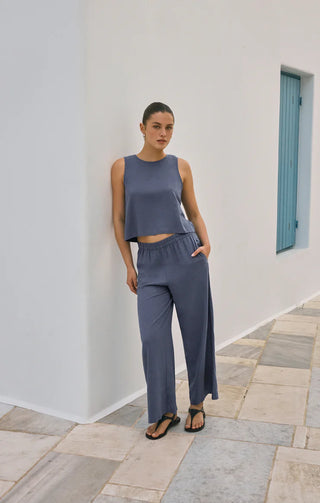 Woman wearing a blue outfit standing against a white wall with a blue door.
