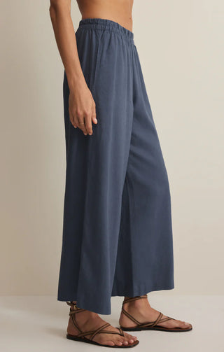 Person wearing blue wide-leg pants on a beige background