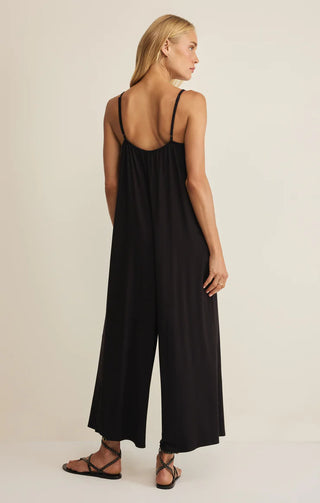 Woman wearing a black jumpsuit on a beige background