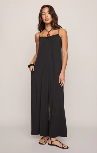 Woman wearing a black jumpsuit on a plain background