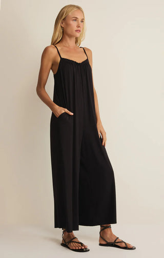 Woman wearing a black slip dress against a beige background