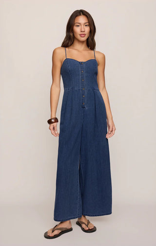 Woman wearing a blue denim jumpsuit on a plain background