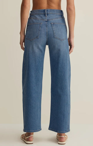 Blue jeans worn by a person on a beige background