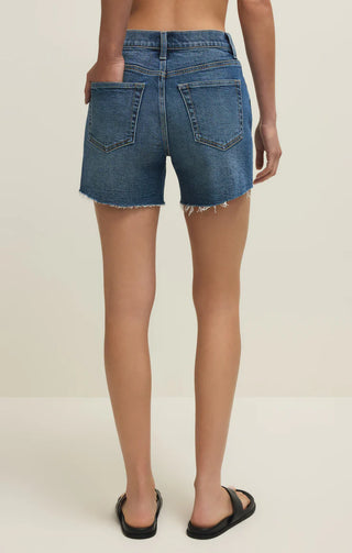 Denim shorts worn by a person on a plain background