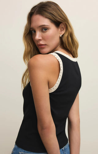 Woman wearing a black tank top with white trim on a plain background