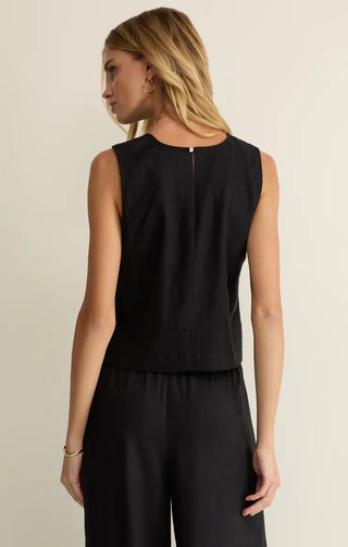 Woman wearing a black sleeveless top and pants on a beige background