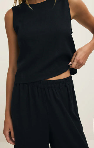 Person wearing a black sleeveless top and black pants on a white background