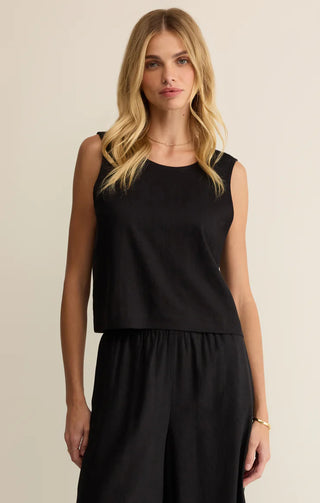 Woman wearing a black sleeveless top and black pants on a beige background