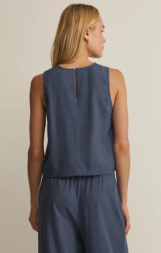 Woman wearing a sleeveless blue top and pants on a beige background
