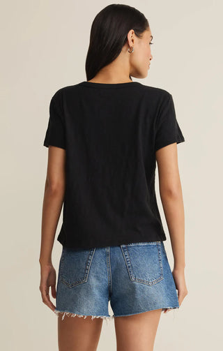 Person wearing a black t-shirt and denim shorts on a beige background