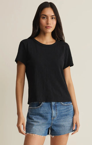 Woman wearing a black t-shirt and denim shorts on a beige background