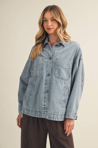 Woman wearing a light blue denim shirt against a beige background