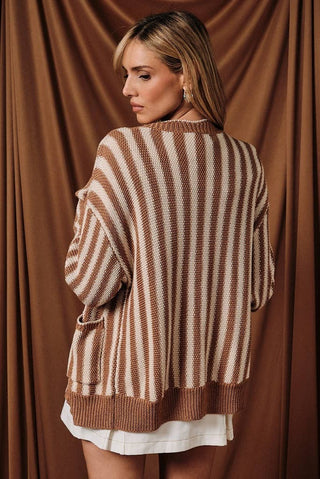 Woman wearing a brown and beige striped sweater against a brown curtain background