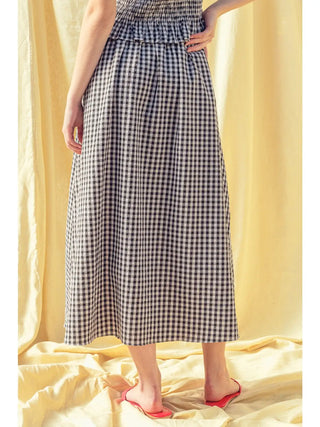 Person wearing a black and white checkered dress against a yellow curtain background