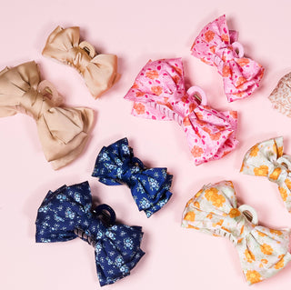 Collection of colorful floral hair bows on a pink background