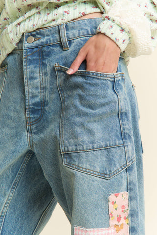 Close-up of blue jeans with floral patch on a neutral background