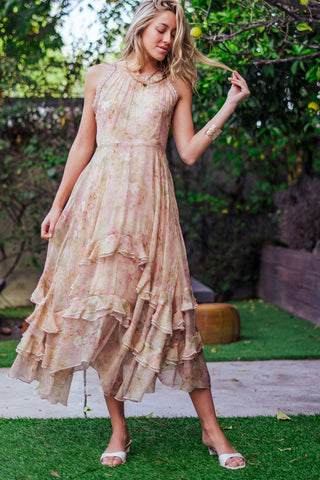 Woman wearing a floral dress standing outdoors with greenery in the background