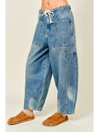Blue denim pants with a drawstring waist on a plain background