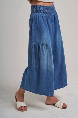 Blue denim skirt worn by a person on a plain background