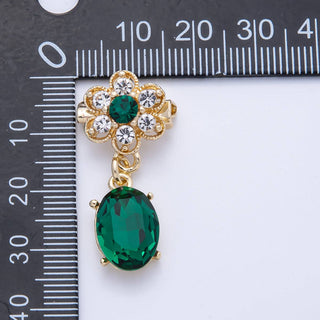 Gold and green gemstone earring next to a ruler for size reference