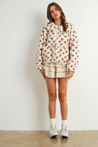 Woman wearing a floral outfit with white sneakers on a plain background