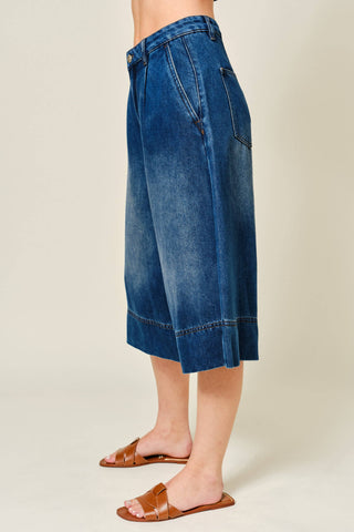 Blue denim skirt worn by a person on a plain background