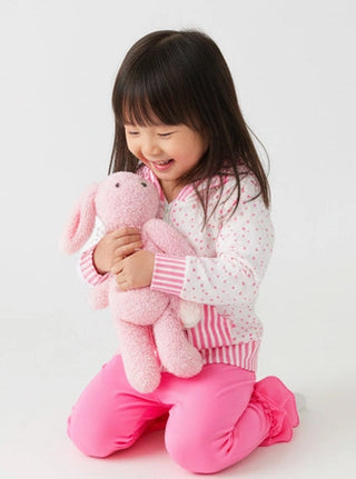 Child holding a pink plush toy against a white background