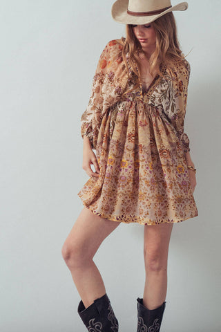 Woman wearing a floral dress, cowboy hat, and boots on a plain background