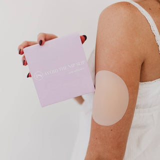 Person applying a adhesive patch on their arm with a branded box in the background.