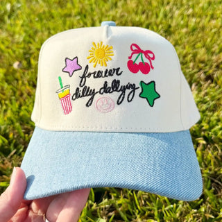 Cap with colorful designs and text held in front of grass