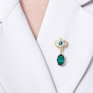 Gold earring with a green gemstone on a white background