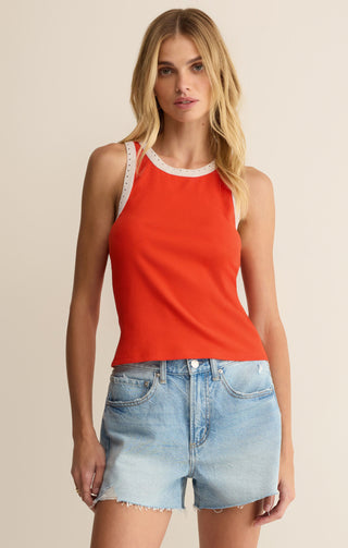 Woman wearing a red tank top and denim shorts on a beige background
