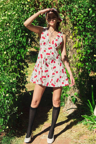 Woman in a floral dress standing outdoors against a green leafy background