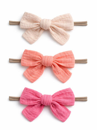 Three pink hair bows on brown bands against a white background