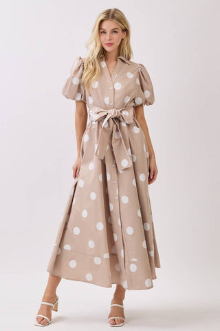 Woman wearing a beige dress with white polka dots on a white background