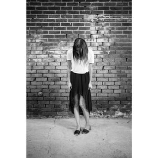 Person standing against a brick wall in black and white.