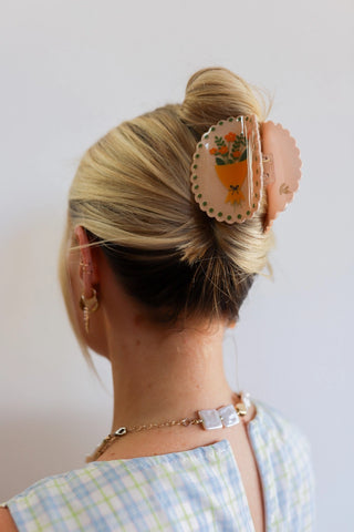 Person with a decorative hair clip in their hair against a plain background