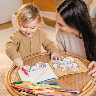 Woman and child coloring together with crayons on a wooden table.