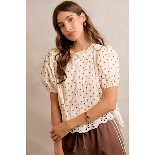 Woman wearing a polka dot blouse with a neutral background