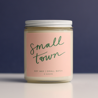 Candle jar labeled 'Small Town' with a pink label on a dark background