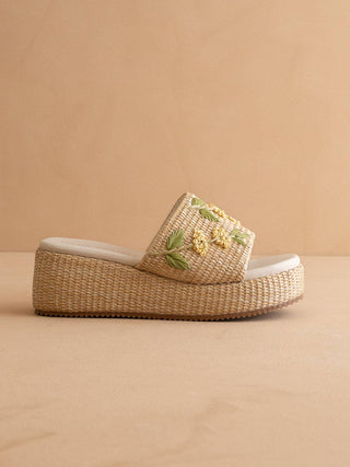 Woven sandal with floral embroidery on a beige background