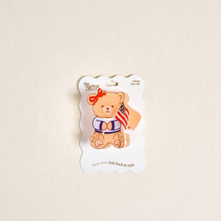 Teddy bear with a bow and American flag on a white card with 'the little effect' branding.