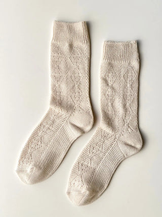 Pair of beige knitted socks on a light gray background